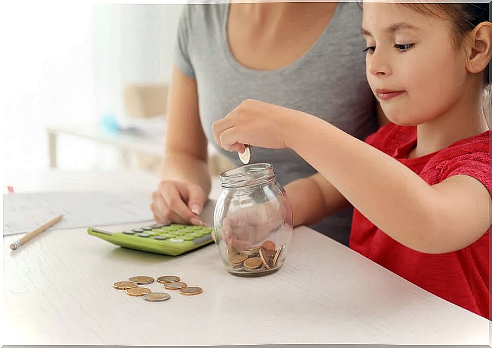 Little girl putting coins into a pot with her mother to learn how to save.