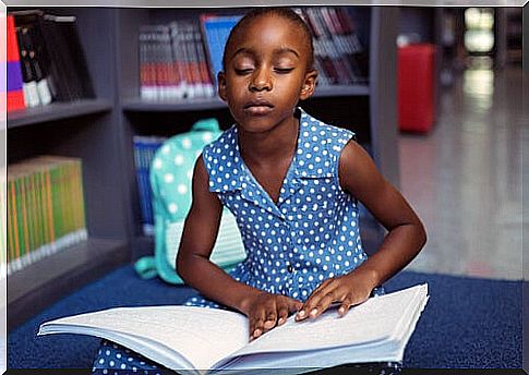 Girl reading braille in the library.