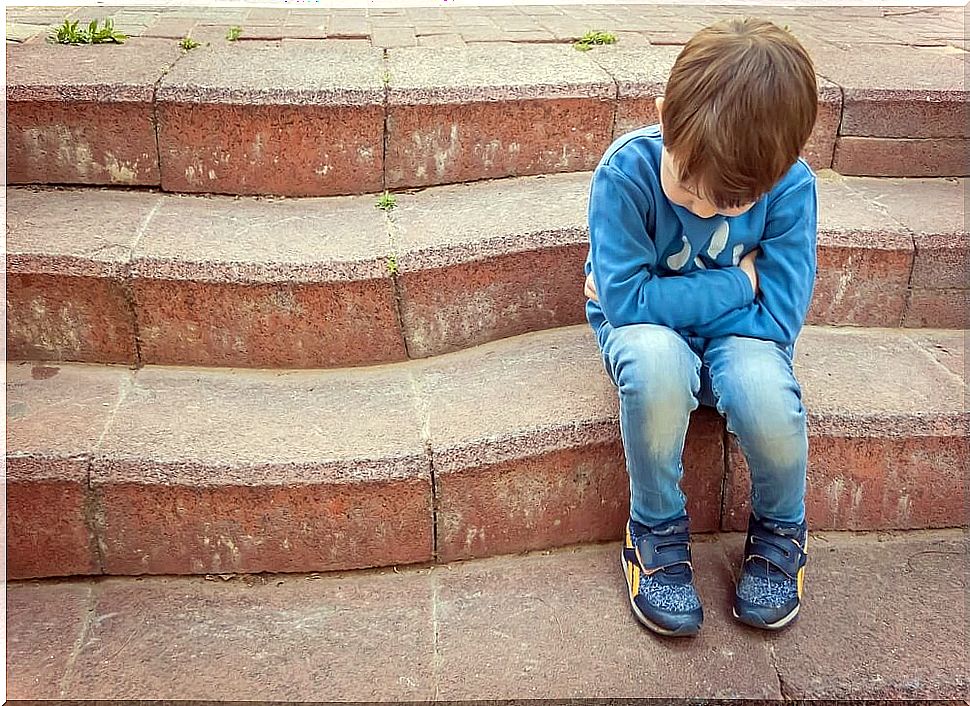 Child who suffers bullying or bullying sitting on some stairs alone.