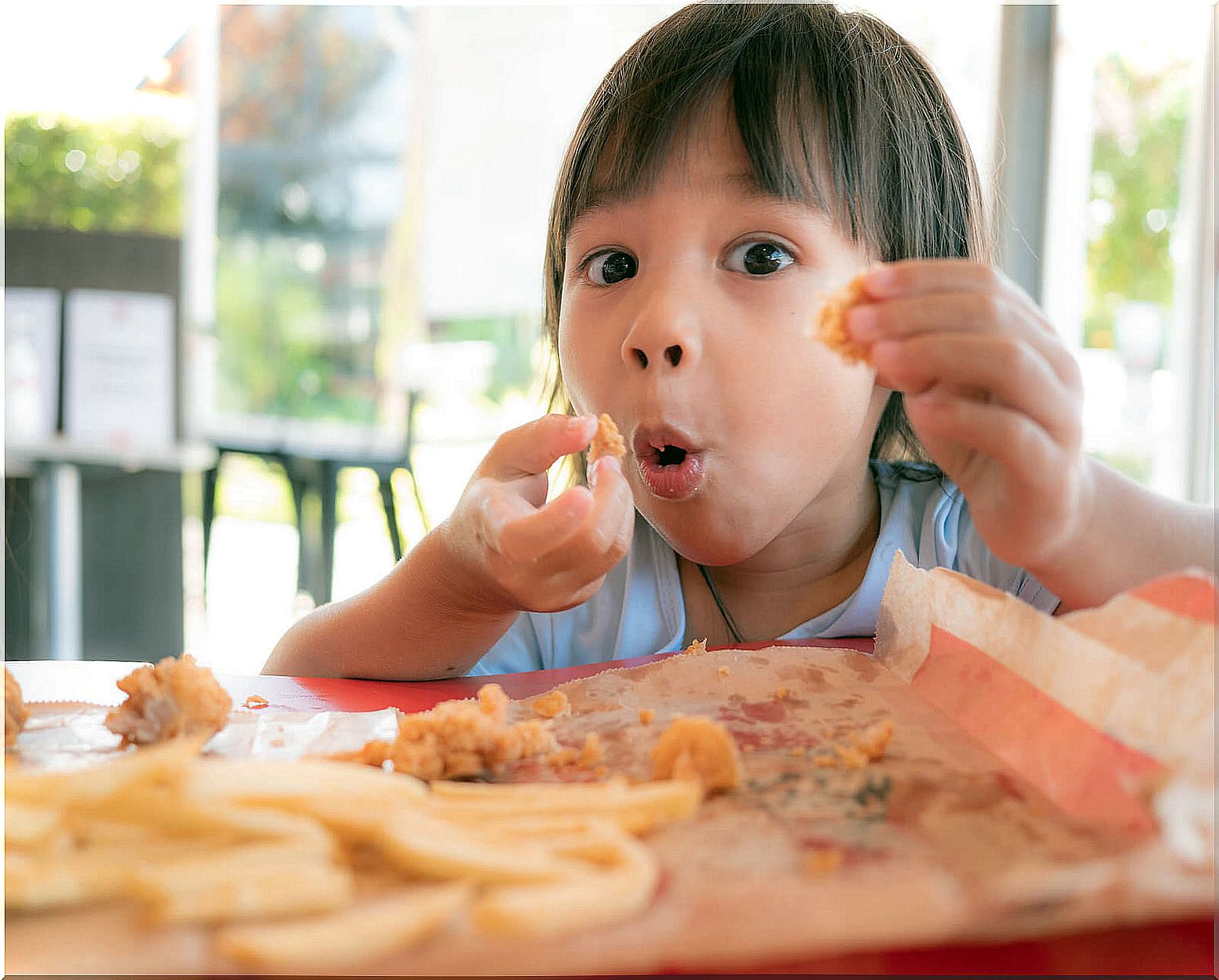 Little girl eating potato chips with food additives.