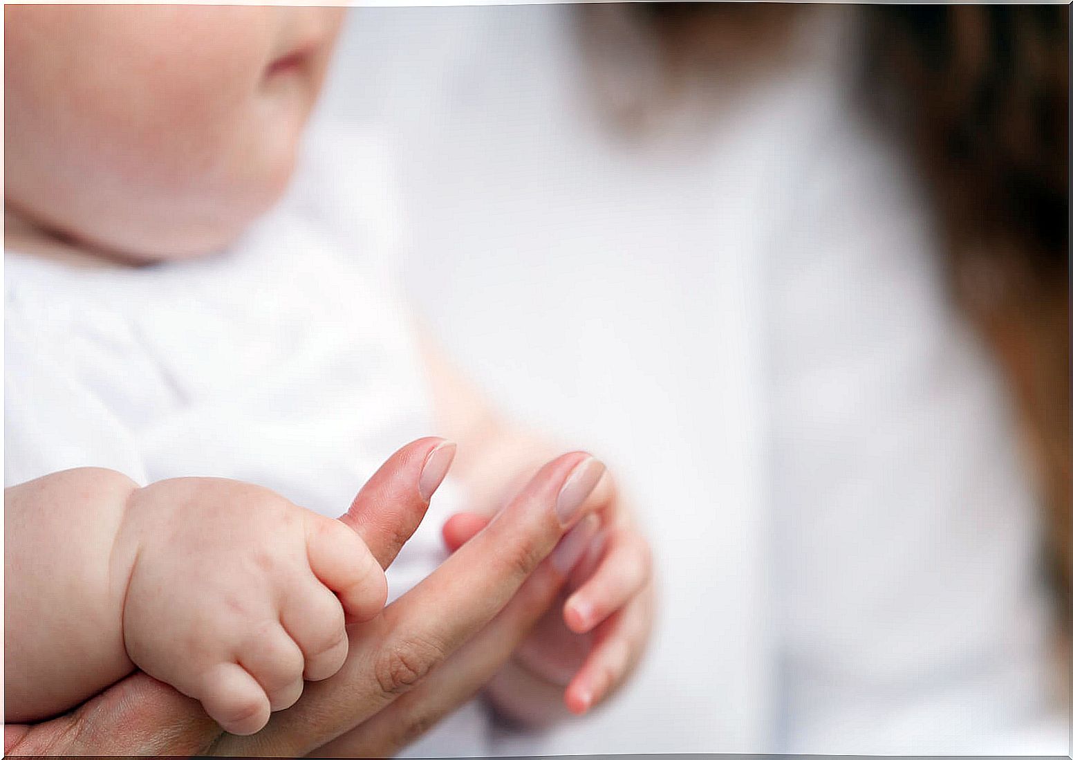 Baby holding the finger of his mother.