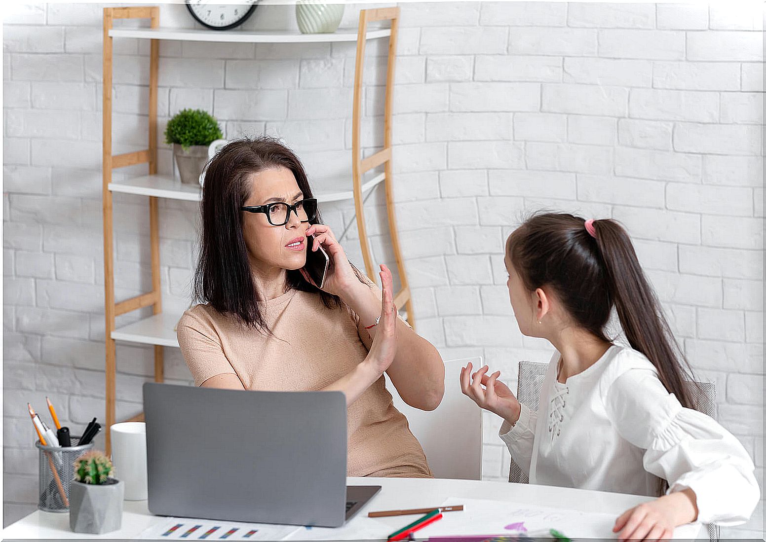 Mother working while making her daughter wait because she does not want to learn to delegate.