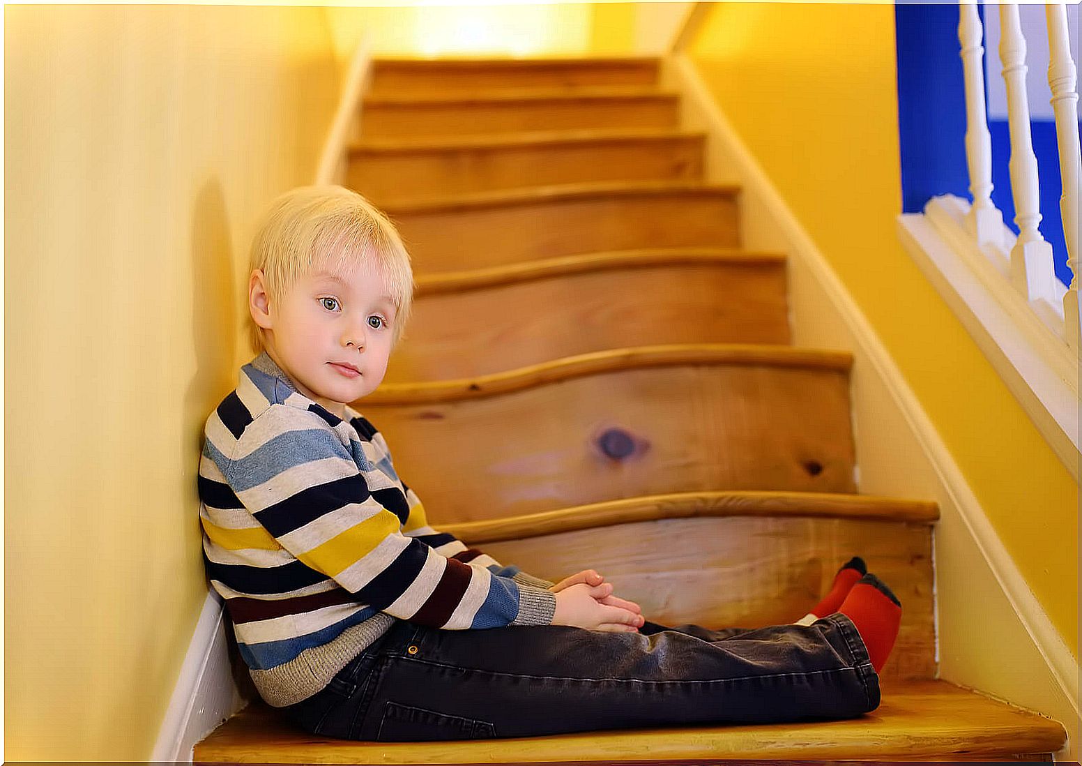 Obedient child sitting on the stairs at home.