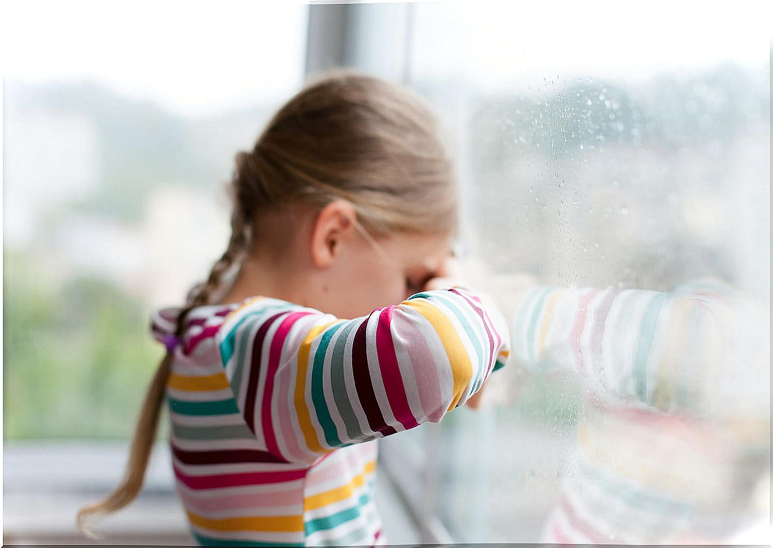 Girl with pluviophobia looking at the rain through the window.