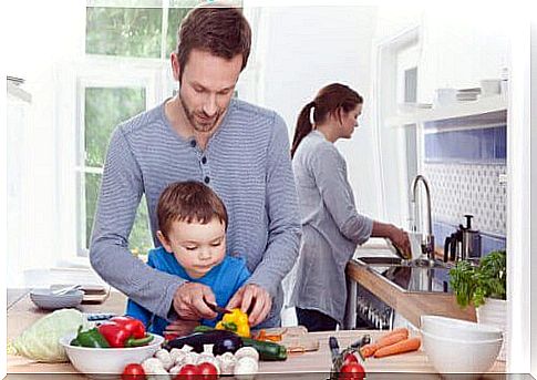 Child in the kitchen with his parents, who do teamwork.