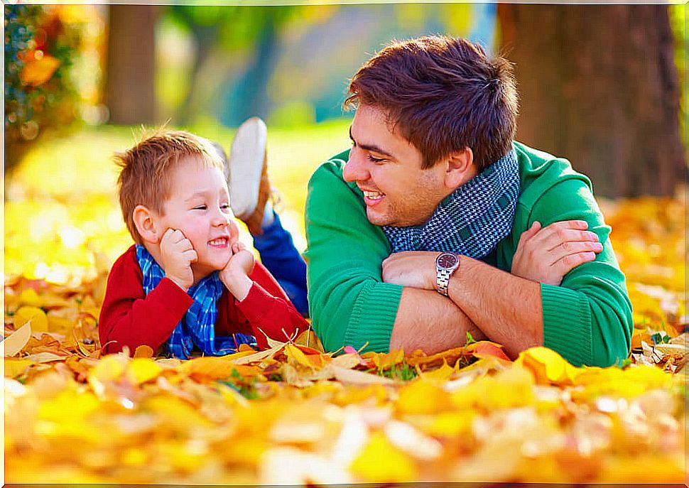 Father and son talking lying on the dry leaves on the ground.