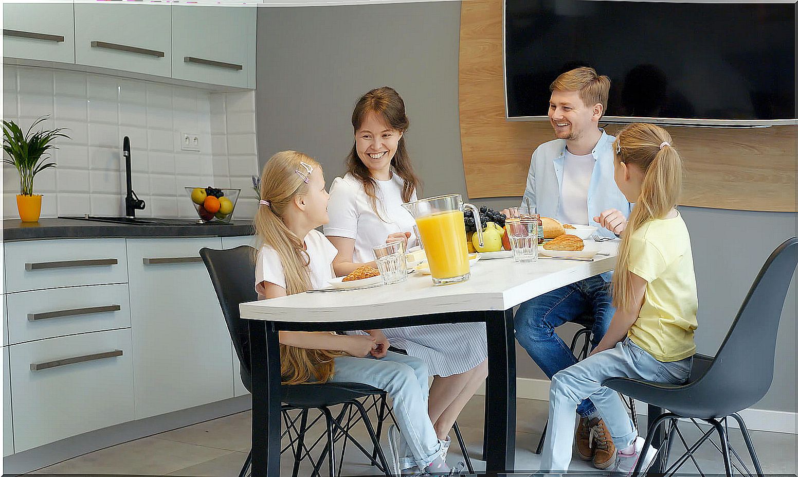 Parents having breakfast with their daughters.